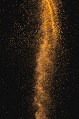 Close up of orange sand thrown in the air and copy space on black background