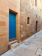New house with beautiful blue traditional Maltese door and an old house classed in limestone in Victoria on Gozo island, Malta