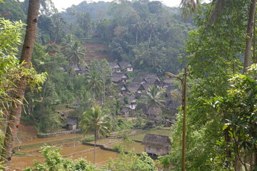 A traditional Indonesian village surrounded by mountains and rice fields called Kampung Naga. 