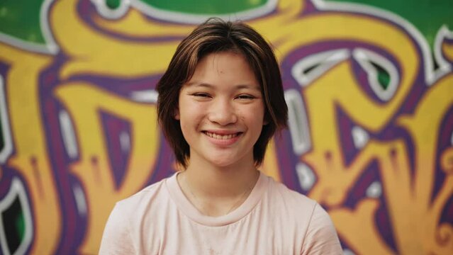 Portrait Of Young Asian Girl Looking At Camera Close Up. Head Shot And Front View Of Joyful Japanese Or Glad Chinese Child Posing On Colorful Background. Cool Life And Diverse Culture Of Asia Youth