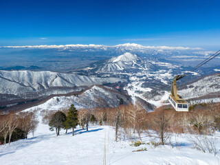 Steep ski slope with a cable car, snowy peaks behind (Ryuo, Nagano, Japan)