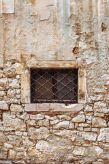 Fototapeta na wymiar Lattice on the window in the old medieval stone wall