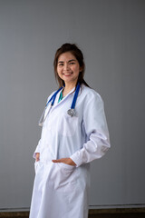 Young Asian female doctor standing on background and holding tappet document , Professional attractive young Asian female doctor in white uniform standing and spread hand with space