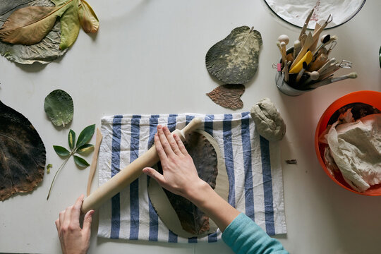 An artisan is using stencil to create decor element out of clay
