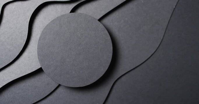 Video of close up of circle of black paper on waves cut out and copy space on black background
