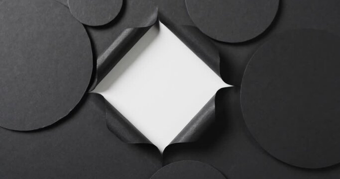 Vertical video of circles of black paper and square cut out with copy space on white background