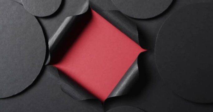 Vertical video of circles of black paper and square cut out with copy space on red background