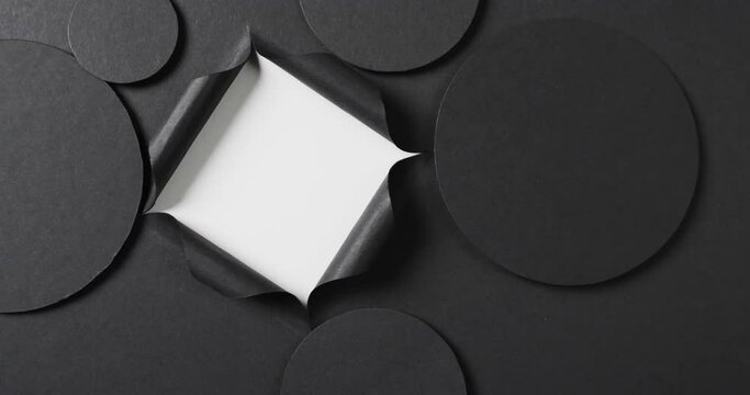 Vertical video of circles of black paper and square cut out with copy space on white background