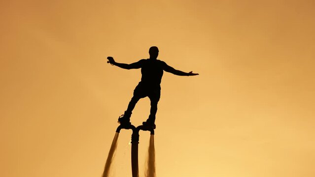 Silhouette of a flyboarder on the background of the sunset sky. Athlete flyboarder on the background of the sun