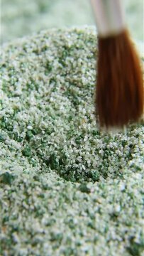 Pale green powder is dug with a brush. ASM video