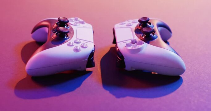 Video of close up of video game pad controllers with copy space on neon background
