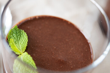 Chocolate mousse dessert garnished with mint leaf on wooden table. Close up