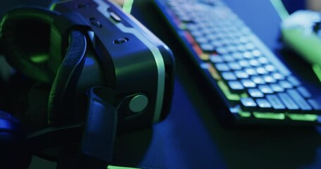 Video of gaming computer and gaming equipment on desk with copy space on neon background