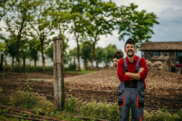 Portrait of a proud male farmer in a working suit standing in front of his farm.