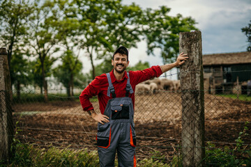 Portrait of a proud male farmer in a working suit standing in front of his farm.