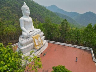 The impressive Big Buddha statue in Pai, Thailand taken high up on a tree-covered hill from the side.