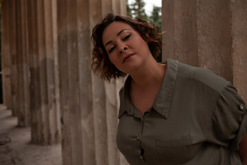 Portraiy of a beautiful girl is wearing a khaki t-shirt, the overweight woman posing against stone biege wall. The fashion outfit for plus-size woman for the city, minimalizm urban style clothes