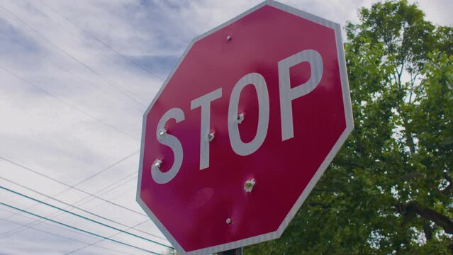 stop sign riddled with bullet holes, welcome to our town, stop violence