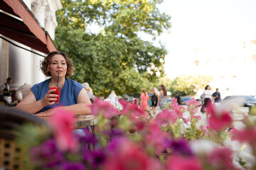 Beautiful young woman sit in cafe with glass of cooly drink. Plus size woman  drink red juice and...