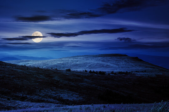 rolling hills on the slopes of high mountains at night. beautiful countryside scenery in full moon light