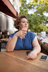 Beautiful young woman sit in cafe with glass of cooly drink. Plus size woman  drink red juice and smiling