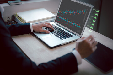 Hand of Businessman or trader touching showing a growing virtual hologram stock on Laptop, Concept invest in trading.planning and strategy, Stock market, Business growth, progress or success concept.