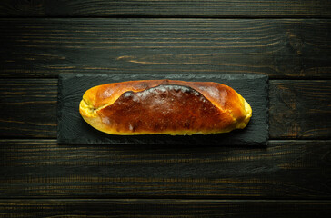 Appetizing baked pie on a black sorting board. Culinary pastry concept for hotel or restaurant on dark background