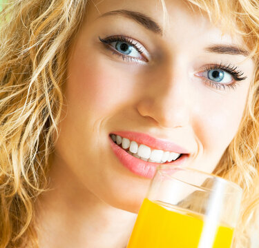 Portrait of happy smiling young beautiful blond woman drinking orange juice
