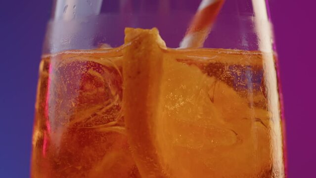 Bartender stirs and drops striped straw into glass with cold summer cocktail with a beautiful movement. Final action serving an aperol cocktail at party. Wonderful refreshing orange liquid