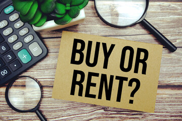 Buy or Rent? text message with calculator and magnifying top view on wooden background