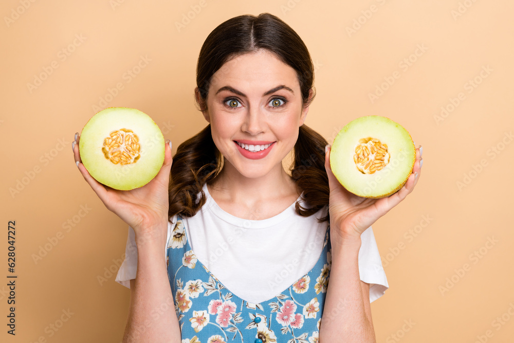 Poster photo of positive impressed excited girl with curly ponytails wear blue overall hands hold melon iso