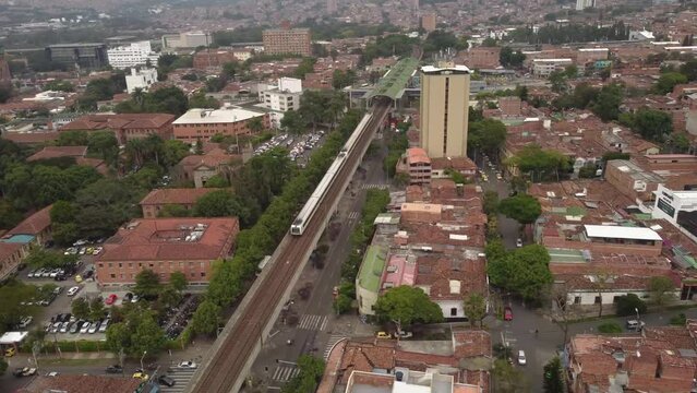 vuelo sobre el barrio prado ubucado en el centro de medellin. se observa tambien el paso del metro