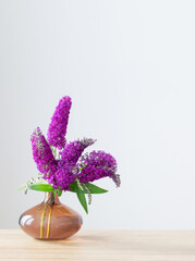 summer lilac in glass vase on wooden shelf