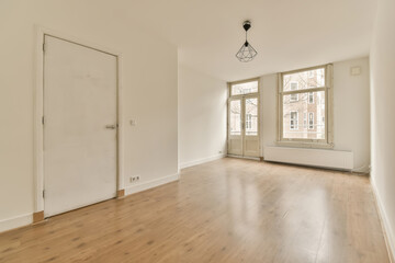 an empty room with wooden floors and white walls, there is a door leading to the left side of the room
