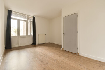 an empty room with wooden floors and white walls, there is a door leading to the left side of the room