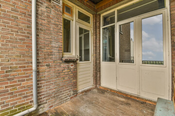 a brick house with two doors and an open window on the front door there is a blue sky in the background