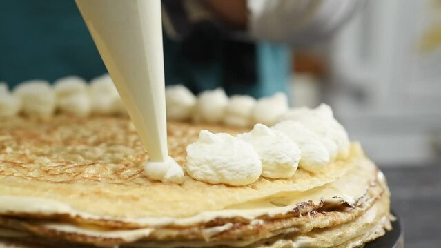 The pastry chef decorating tiramisu crepe cake with whipped cream.
