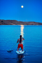 Man at Sup board against full moon at lake