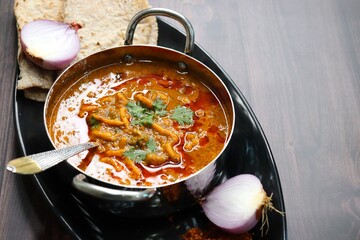 Traditional Sev bhaji or sev tamatar nu Shaak with Jowar Bhakri. Sev is a crisp fried gram flour vermicelli. Served with chopped onion and lemon. with Copy space. Its a sweet and spicy indian curry.