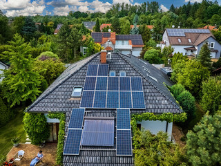 Aerial view of the roofs of houses covered with solar panels. Family houses in gardens,...
