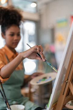 Young artist beautiful african american artist painting picture in studio, closeup