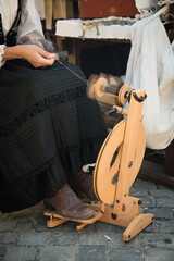 Craftswoman using an spinning wheel to turn wool into yarn