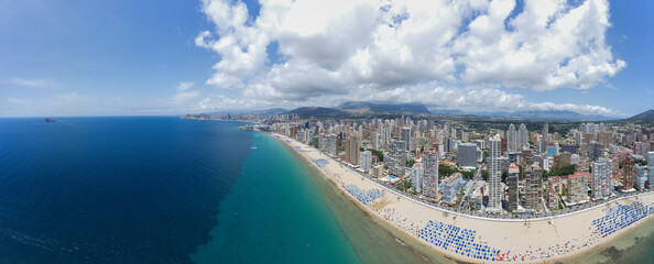 Extremely wide angle panoramic aerial photo of the city of Benidorm in Spain showing a panoramic drone view of the whole of Benidorm and the high rise apartments and beach front near the old town