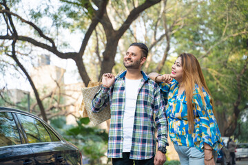 Fototapeta premium Cheerful indian couple walking along the street after shopping