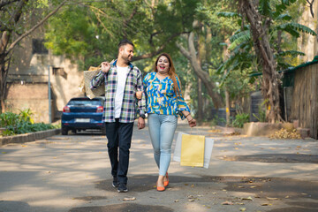 Obraz premium Cheerful indian couple walking along the street after shopping