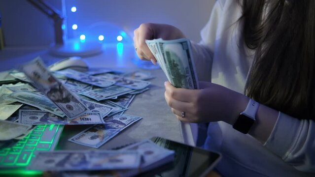 Caucasian Businesswoman counting a lot of money in front of the computer after a working day. Slow motion, close up, hands, fingers, money. 4K