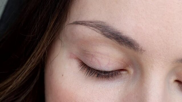 A woman applies eyelash growth product, close up