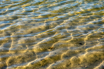 Gentle and relaxing waves of clear water on the shore of a lake.