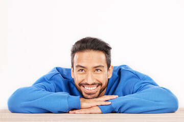 Thinking, wonder and face of man on a white background with ideas, brainstorming and dream by table. Happy, mockup space and isolated male person resting on desk for choice or decision in studio