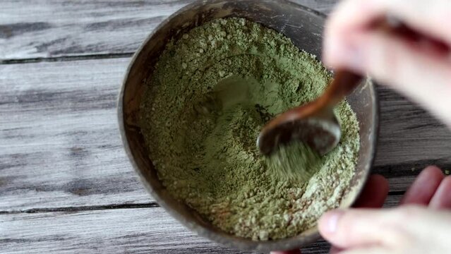 Mixing henna, basma and other herbs in powder to color hair in a natural bowl